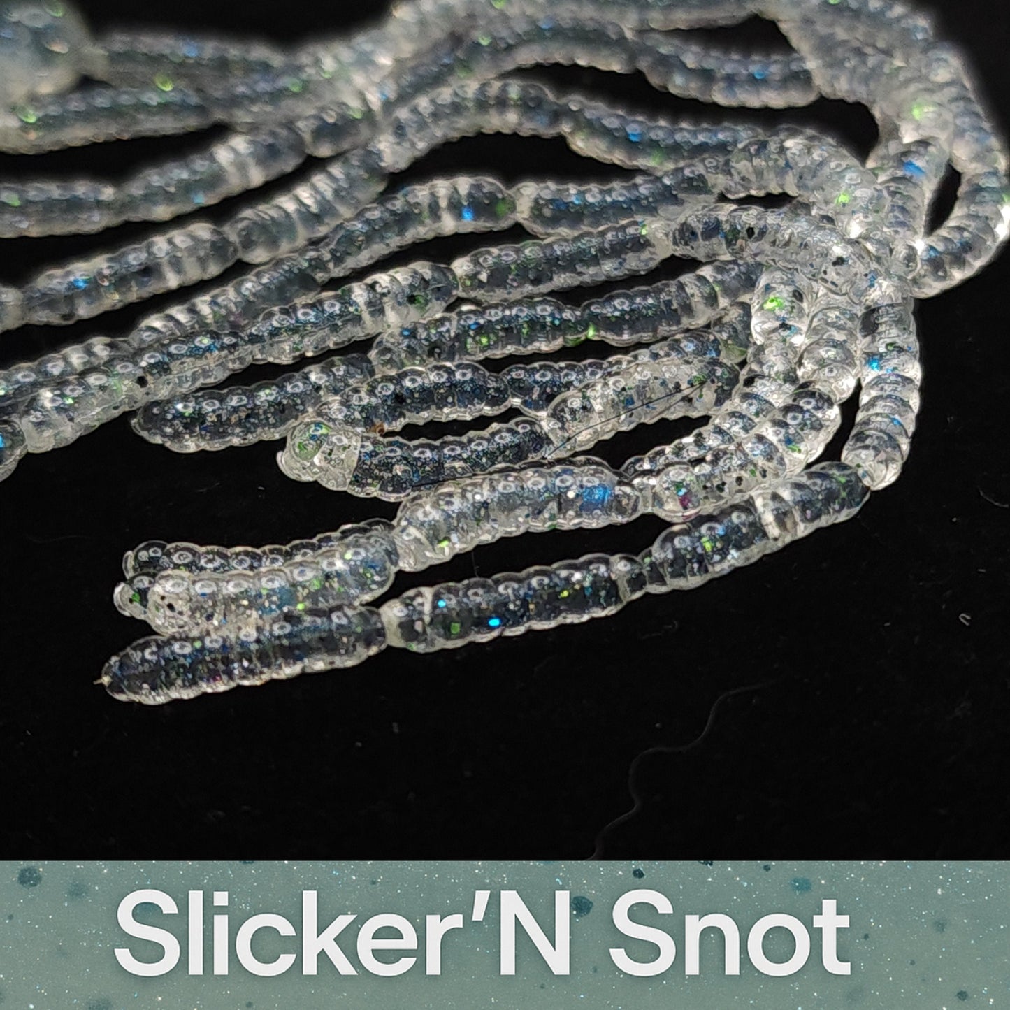 Close-up of 'Slicker'N Snot' artificial fishing baits on a black background