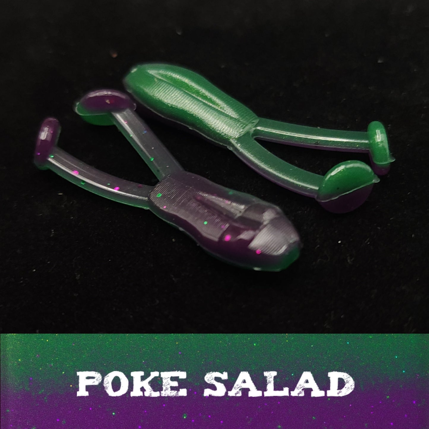 Green and purple plastic frog shaped fishing lures labeled 'Poke Salad' on a black background