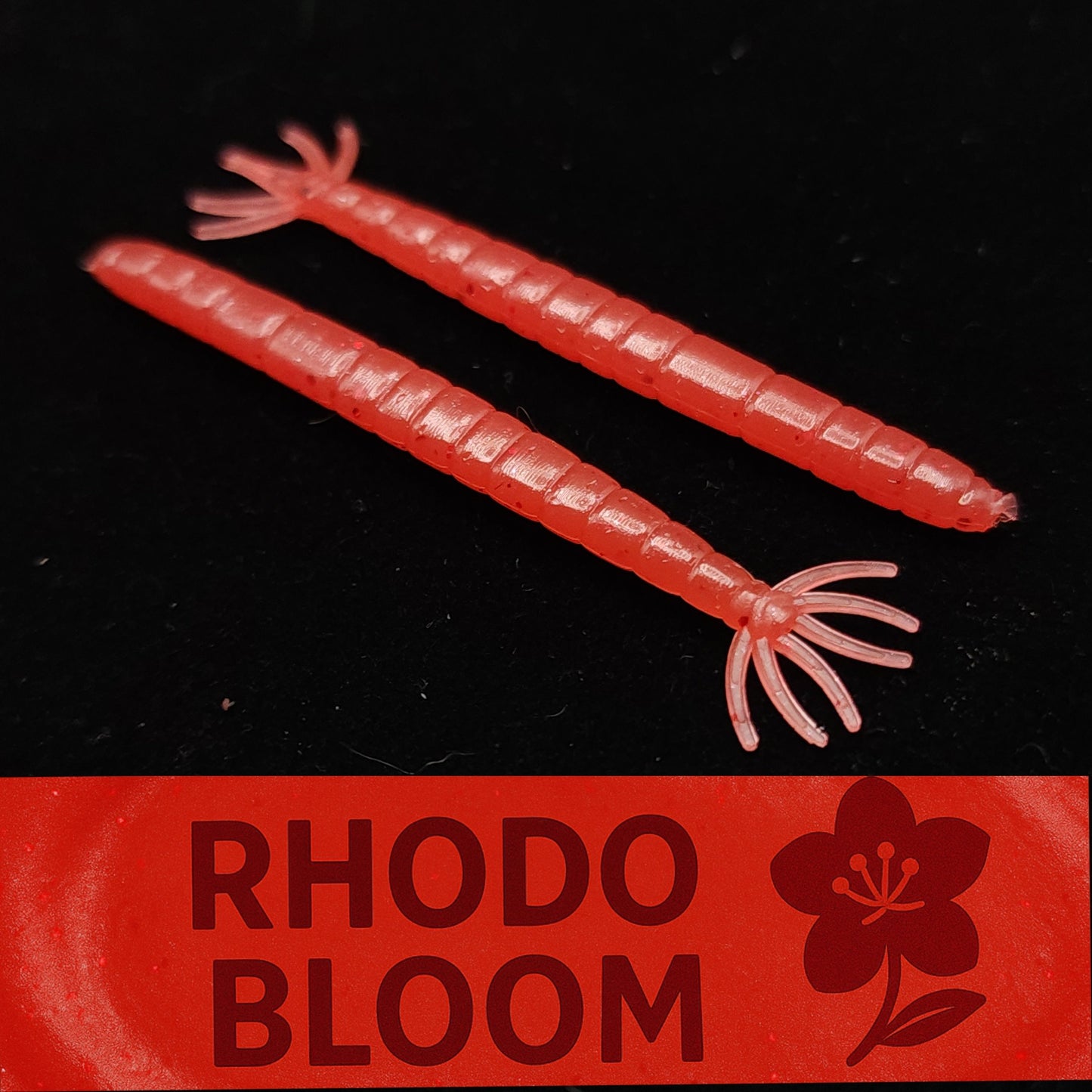 Two red fishing lures with a 'Rhodo Bloom' label on a black background