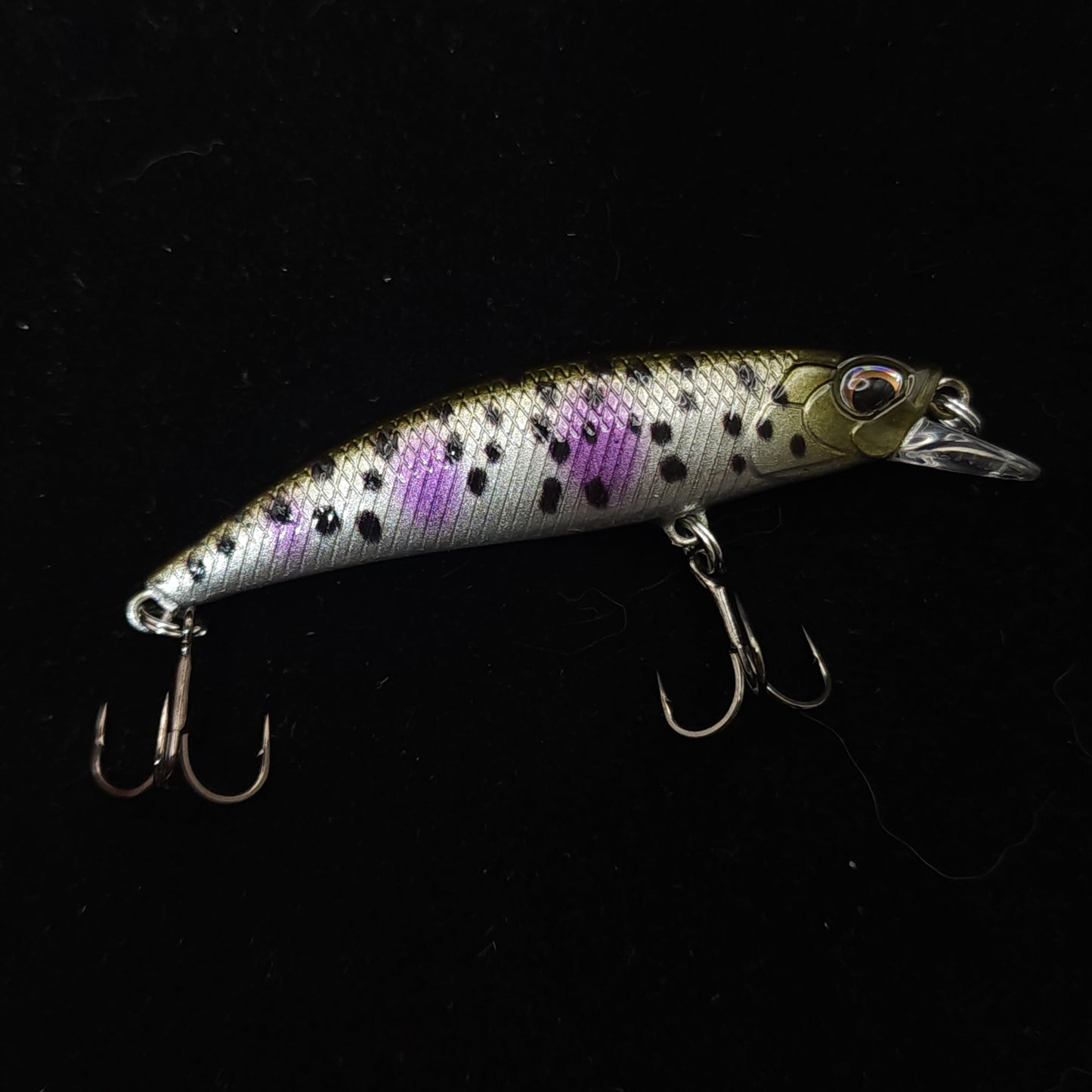 Fishing lure with purple and black pattern on a black background
