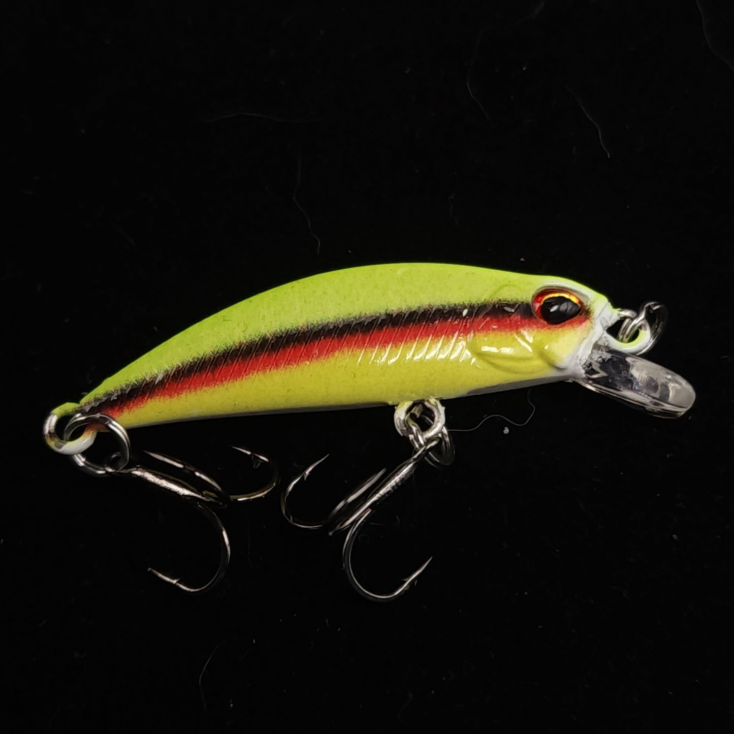 Yellow fishing lure with red and black stripes on a black background