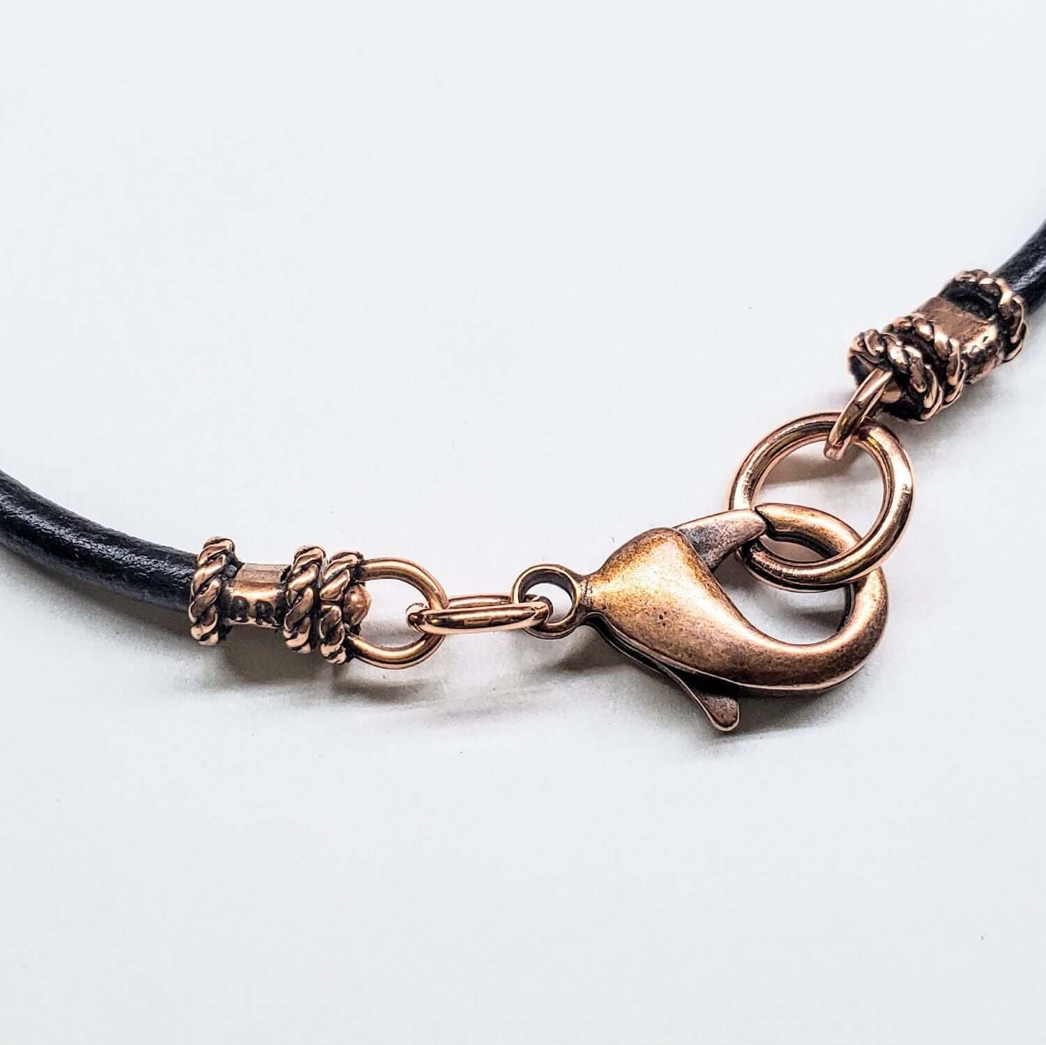 Brass bracelet with black leather strap on a white background