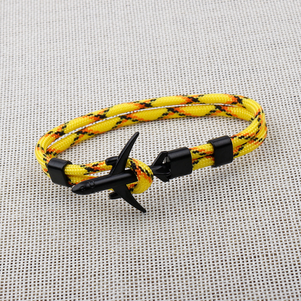 Yellow and black braided bracelet with an anchor charm on a textured gray background