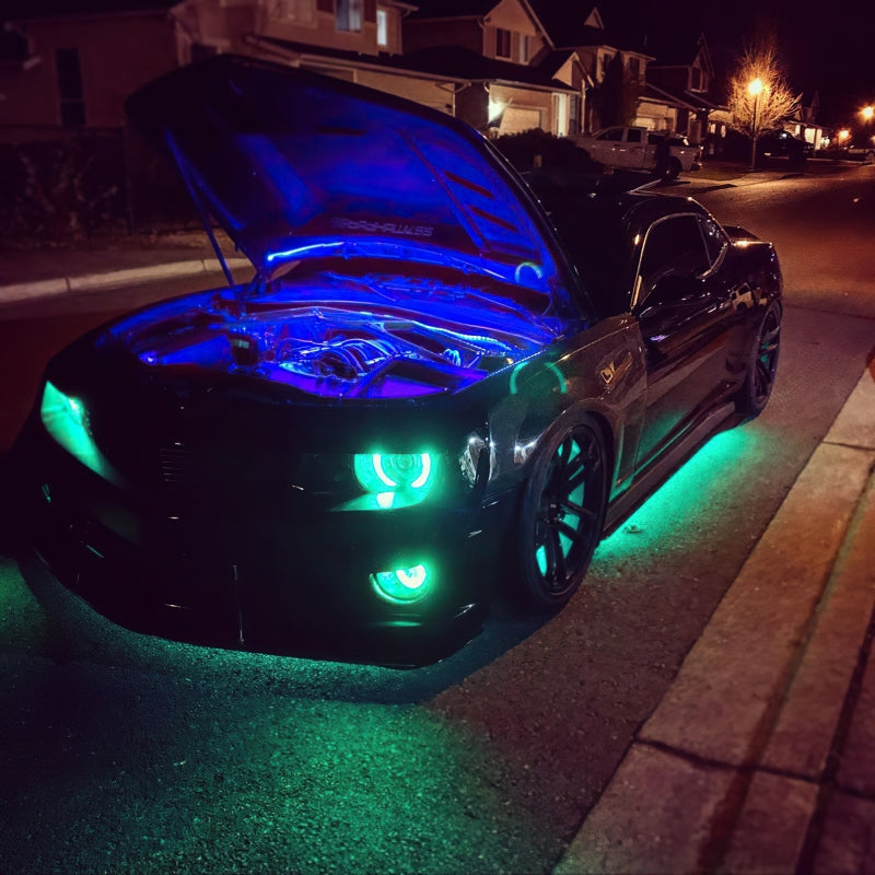 Car with glowing blue and green lights on a residential street at night.