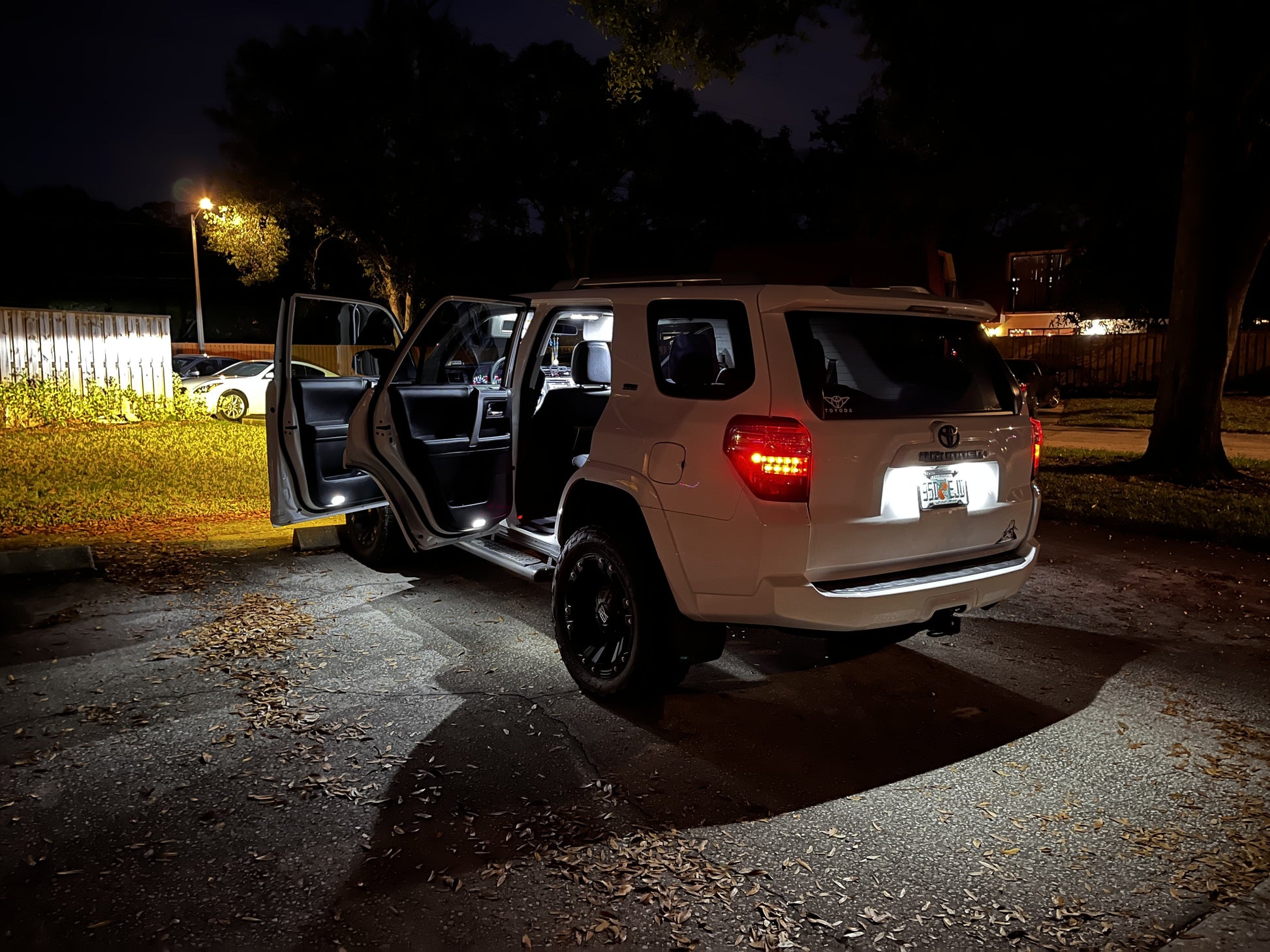 White SUV with open doors parked on a dark street at night