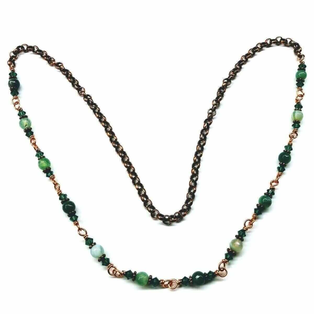 Necklace with green beads and bronze chain on a white background