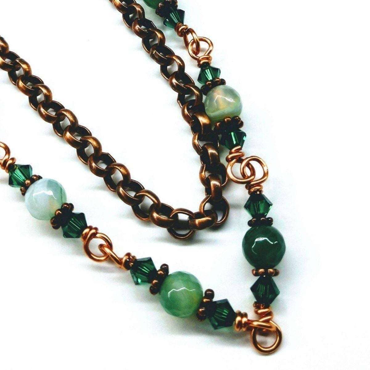 Necklace with green beads and copper chain on a white background