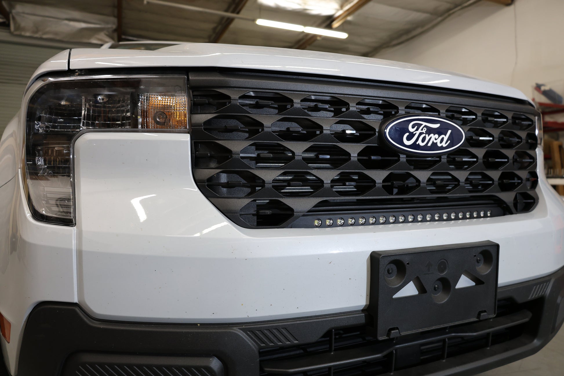 Close-up of a Ford vehicle's front grille and LED light bar with the brand logo.