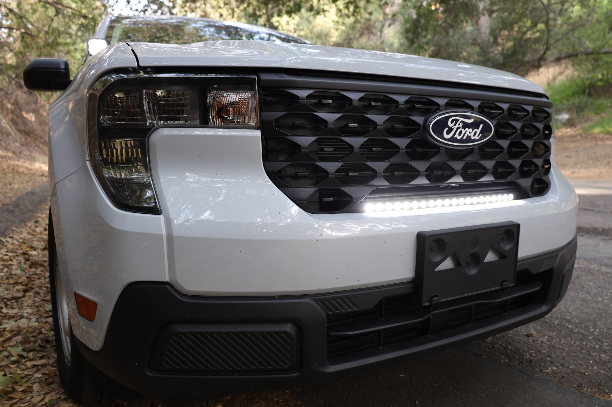 Front view of a white Ford vehicle with a visible grille, headlights and light bar.