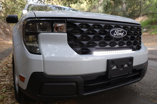 Front view of a white Ford vehicle with a visible grille, headlights and light bar.