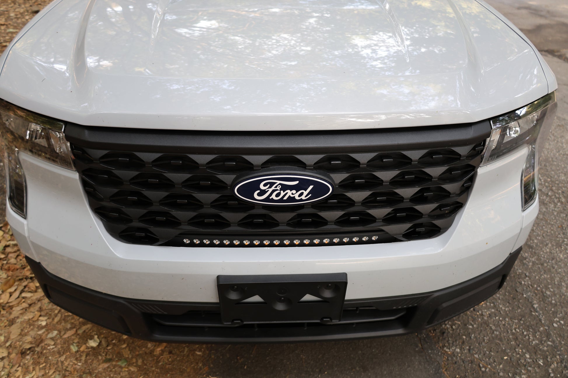 Close-up of a white Ford vehicle's front grille with light bar.