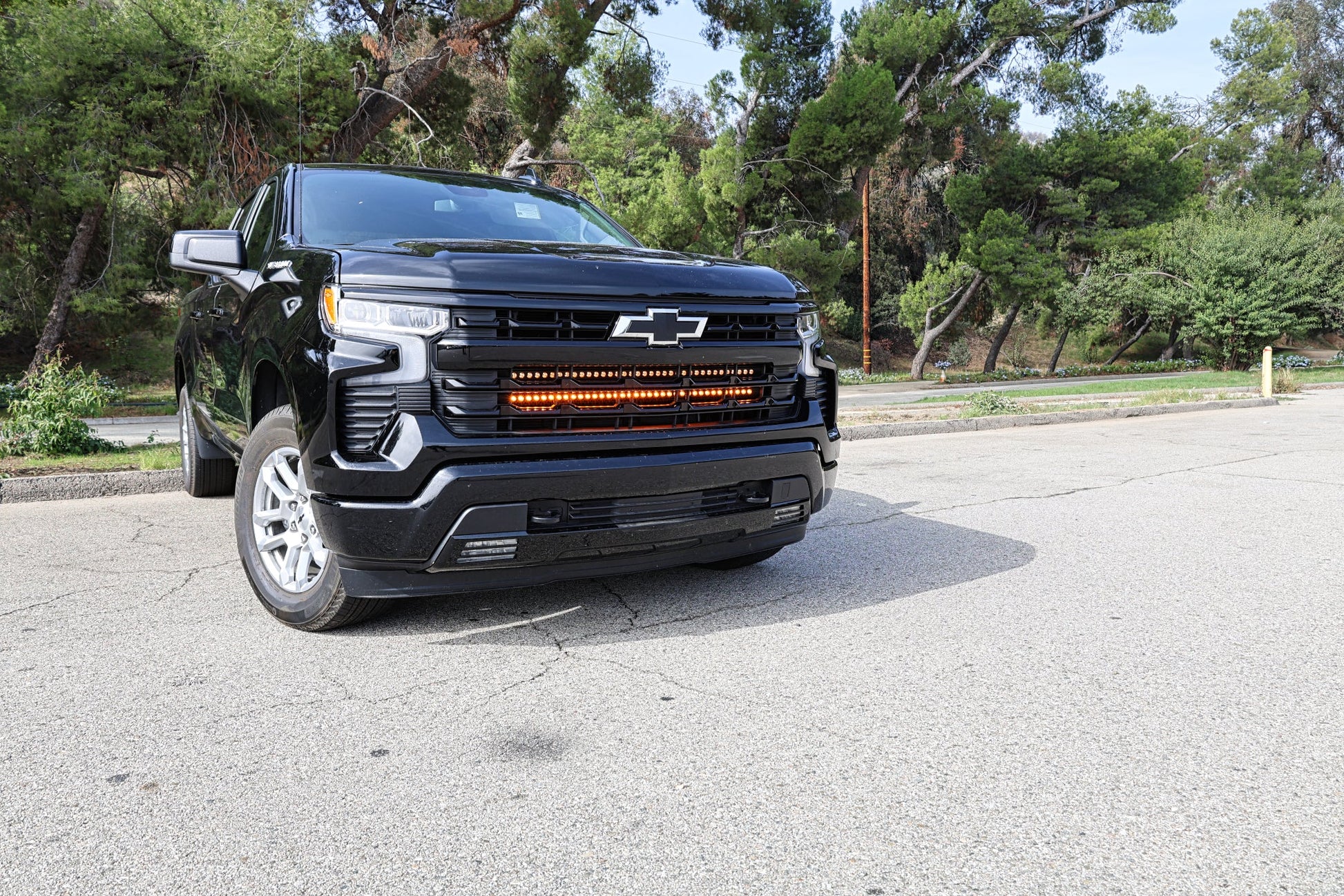 Black Chevrolet truck parked on a paved surface with trees in the background and LED Light Bars mounted on the Grille