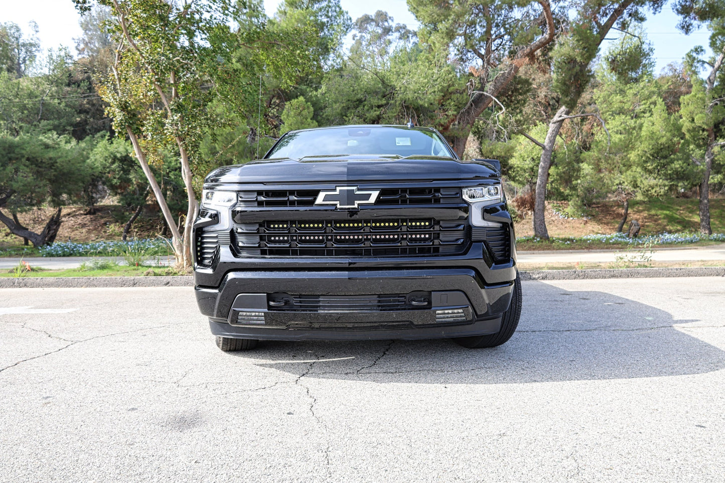 Black Chevrolet truck parked on a paved surface with trees in the background and LED Light Bars on Front 