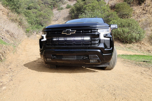 Black Chevrolet truck on a dirt road with a mountainous background and LED Light Bar Mounted on the Grille