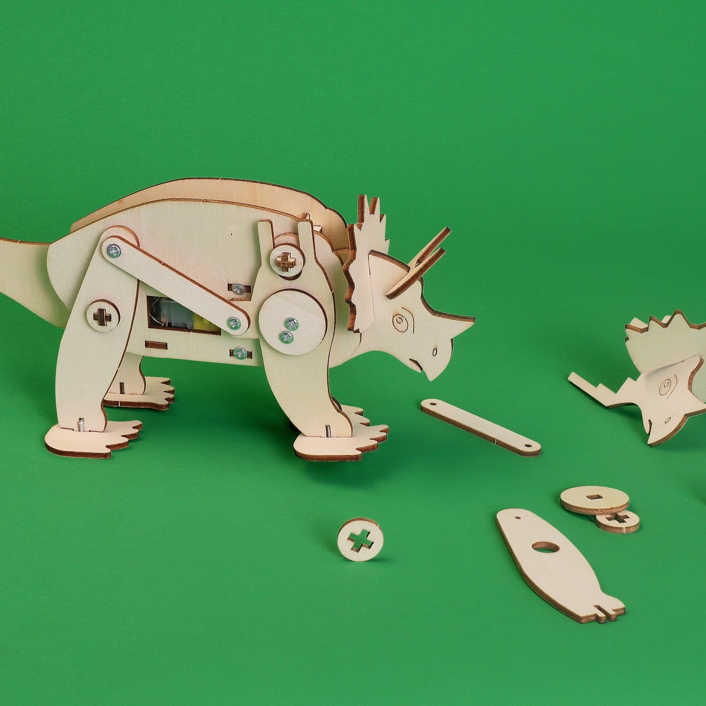 Wooden dinosaur model with missing parts on a green background