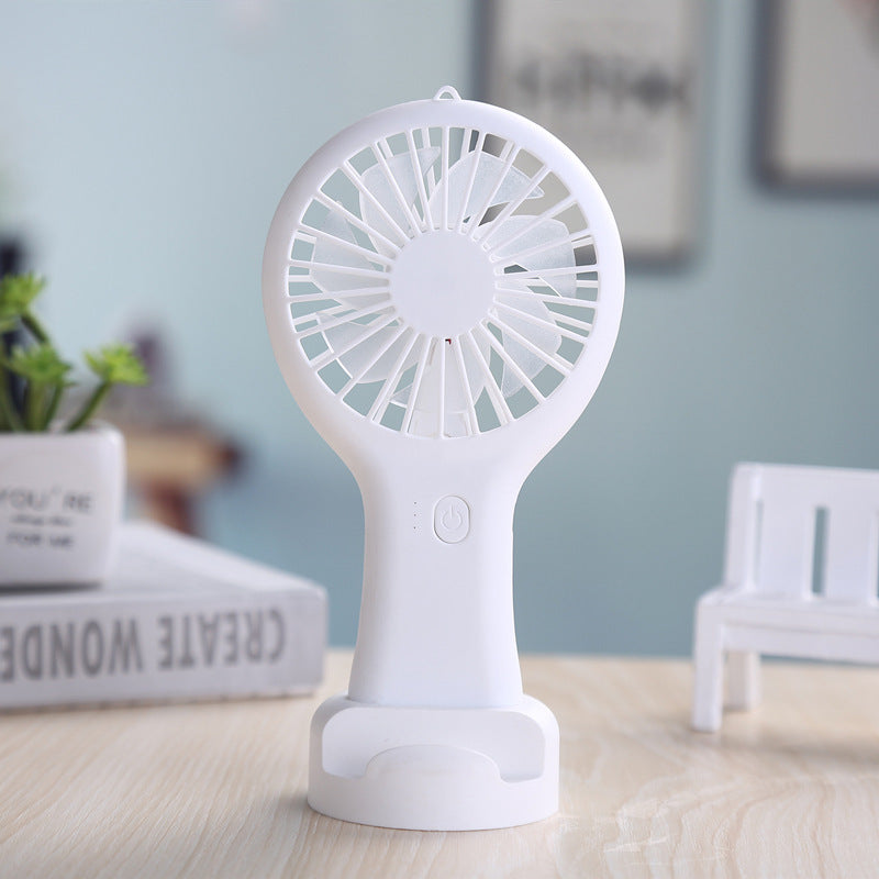 White handheld fan on a wooden surface with a blurred indoor background
