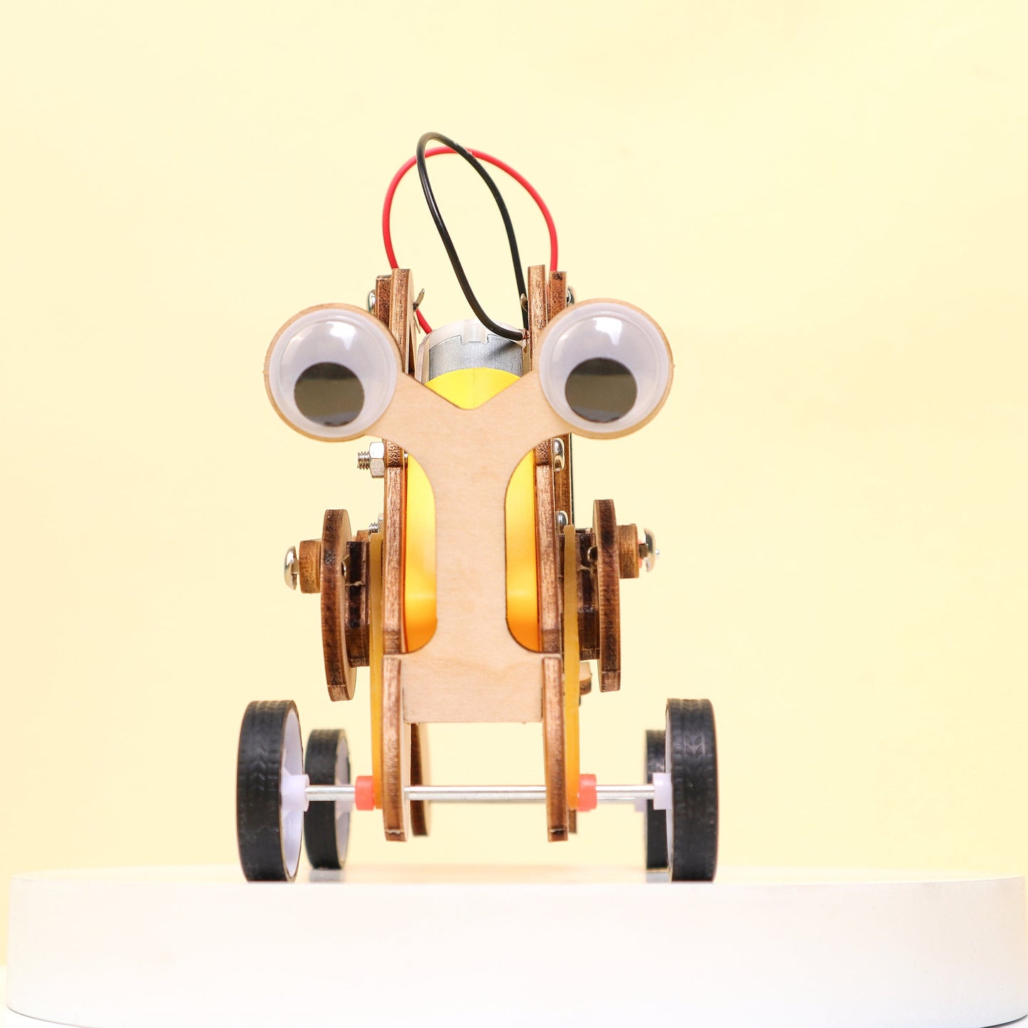 Toy robot with googly eyes on a light yellow background
