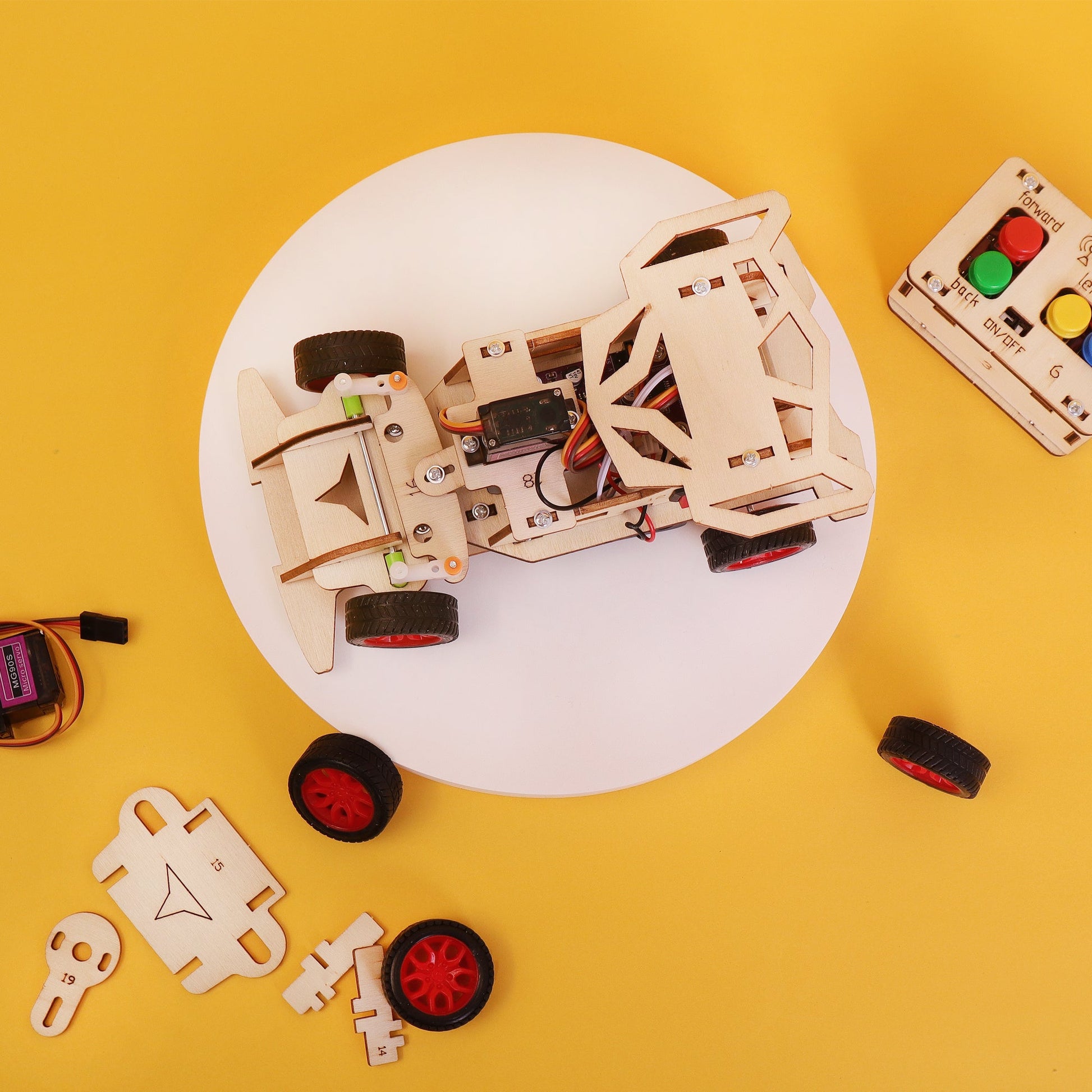 Wooden robot kit on a white plate with remote control on a yellow background