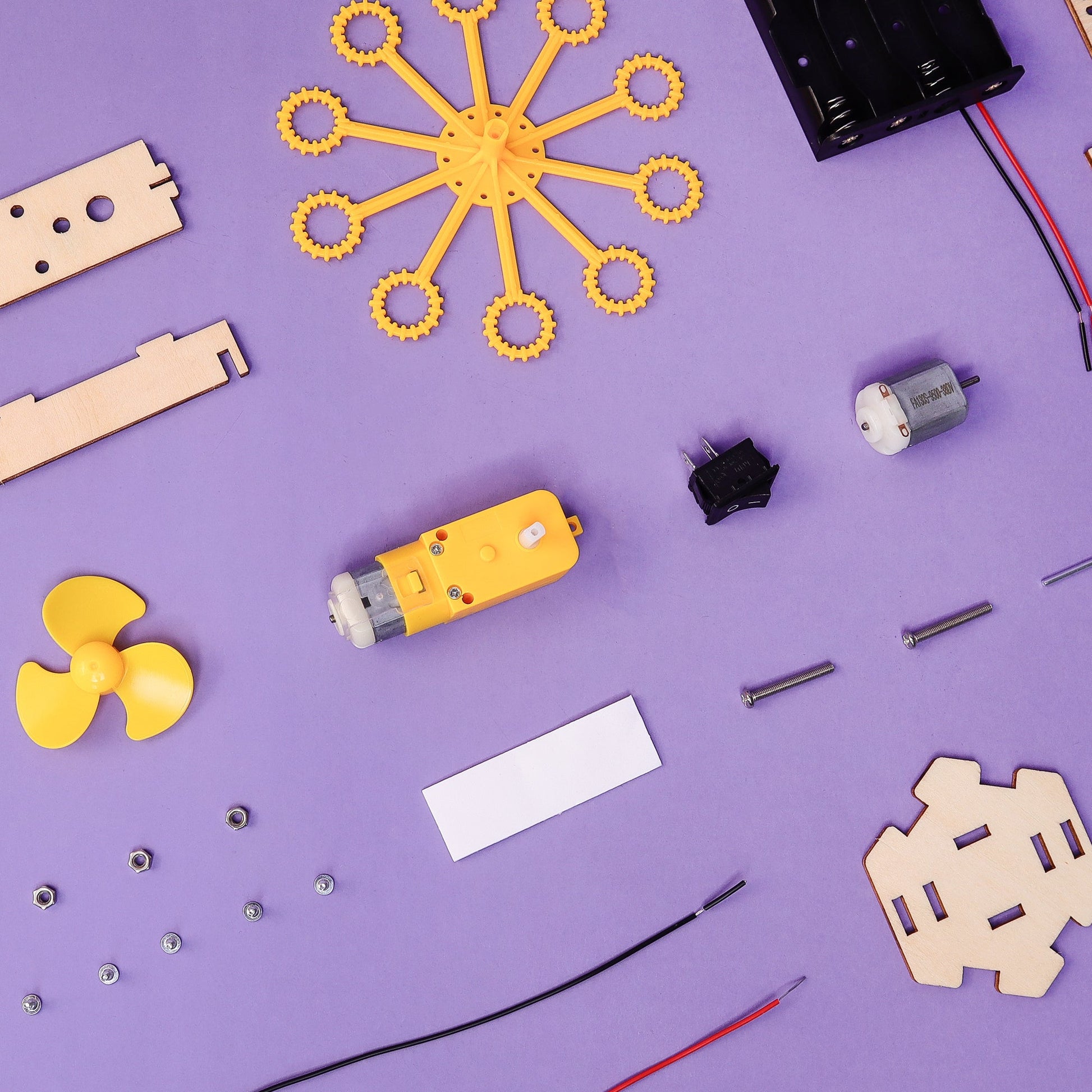 Assorted electronic components for the DIY Bubble Machine Kit on a purple background