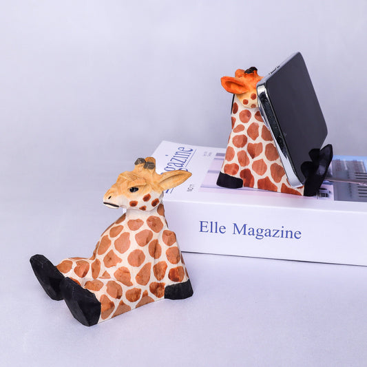 Giraffe-shaped phone stand on a magazine with a white background