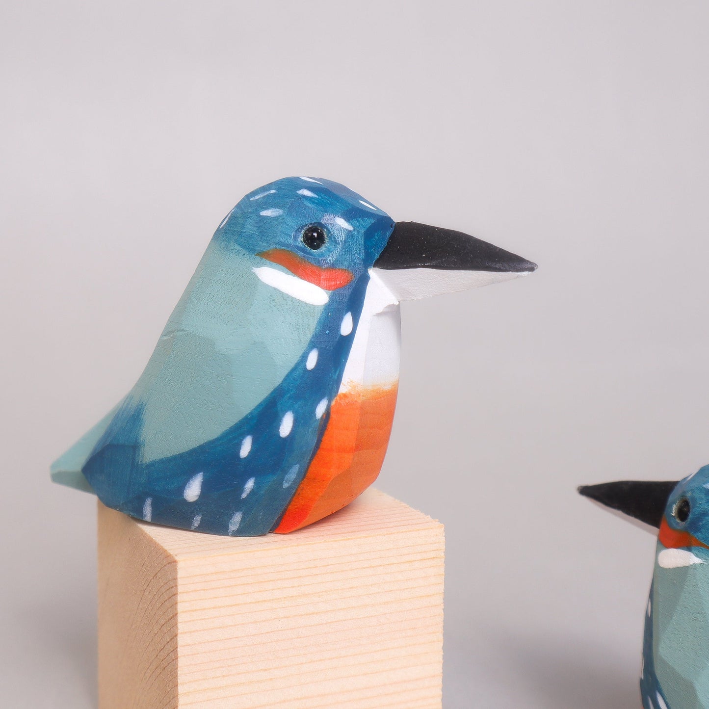 Colorful bird figurine on a wooden block against a light gray background