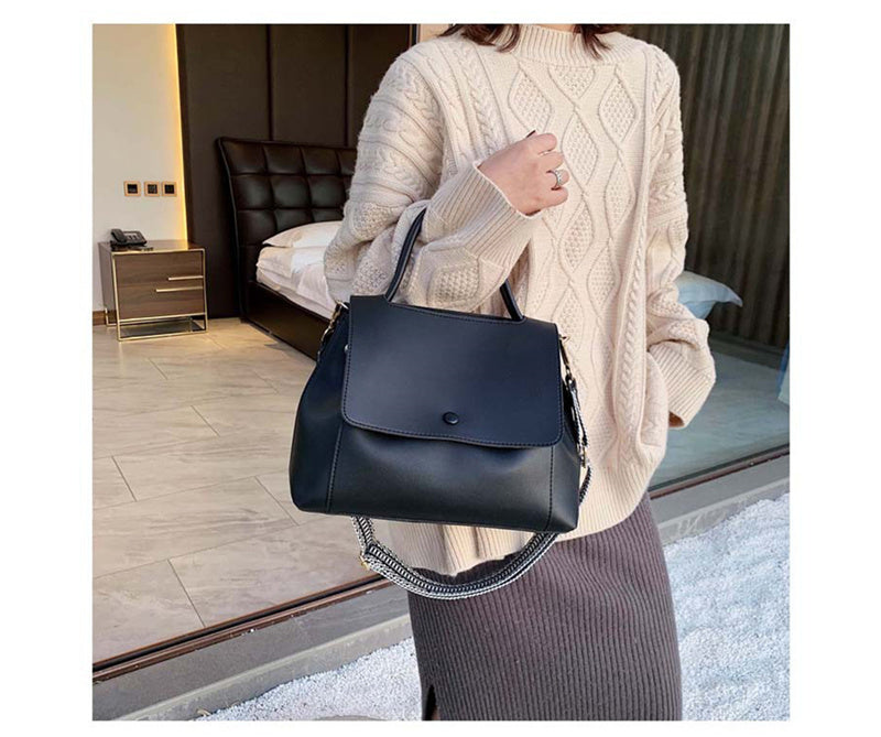 Person holding a black handbag in an indoor setting