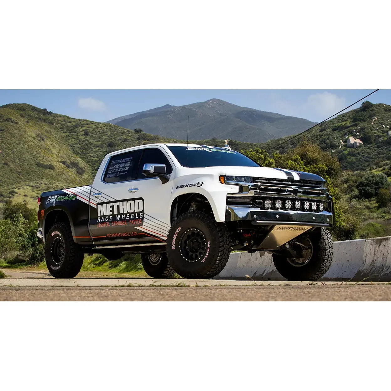 White pickup truck with black and red accents on a mountain road