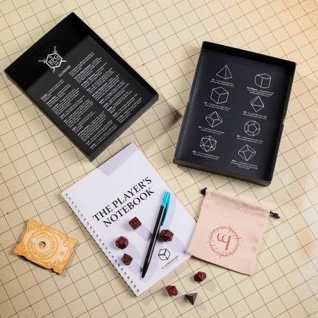 Collection of gaming accessories including a notebook, dice, and pouch on a grid background