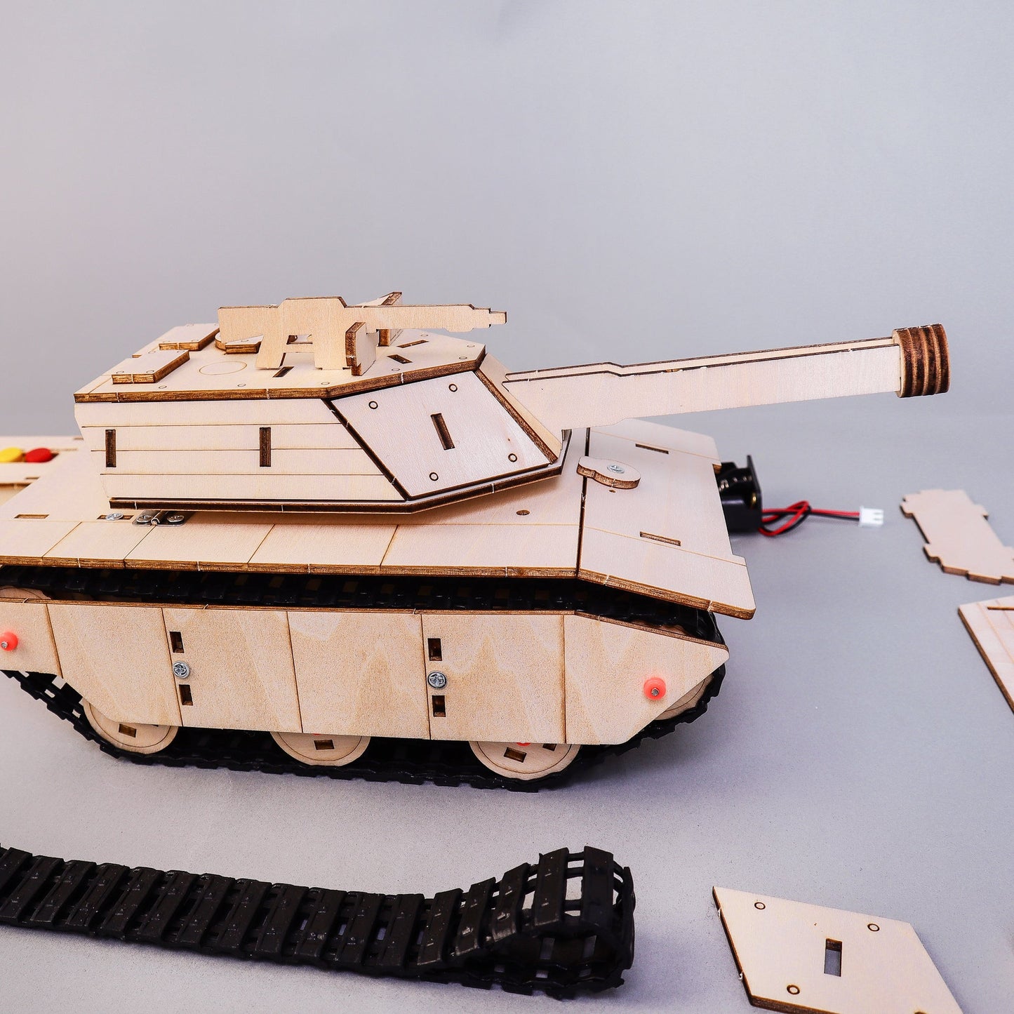 Wooden tank model kit with parts on a gray background