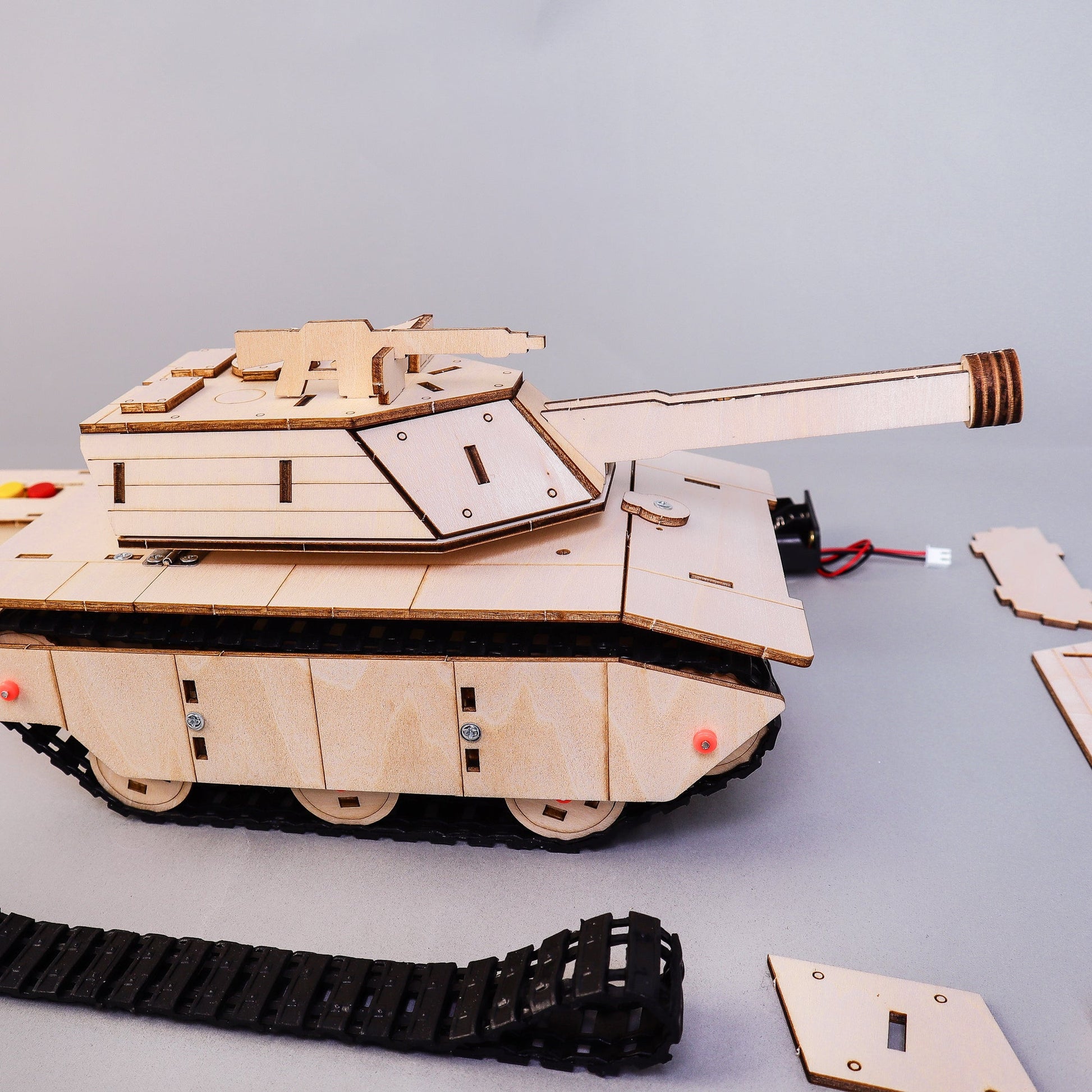 Wooden tank model kit with parts on a gray background