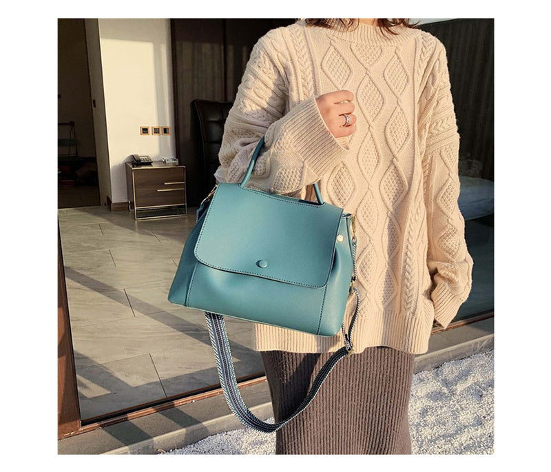 Person holding a teal handbag indoors