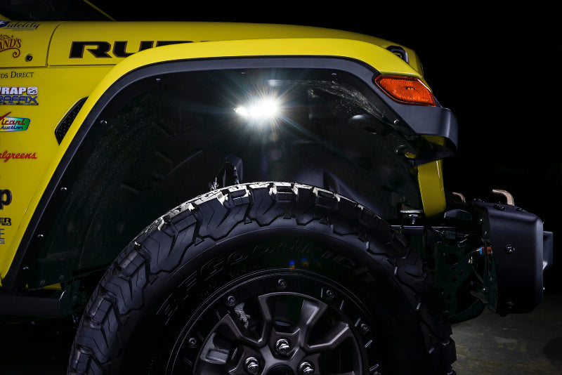 Close-up of a yellow off-road vehicle with underbody lighting at night.