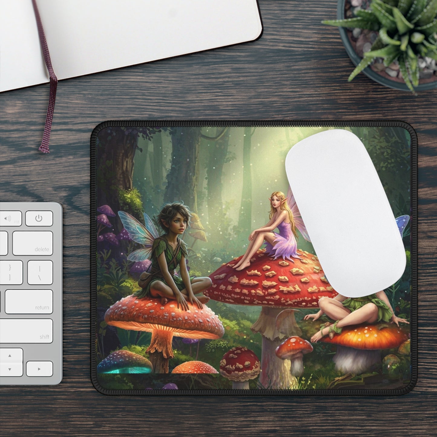 Mouse pad with fairy design on a wooden desk with a keyboard and plant.