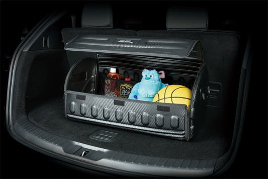 Car trunk with a storage compartment open, containing a teddy bear, bottle, and ball.