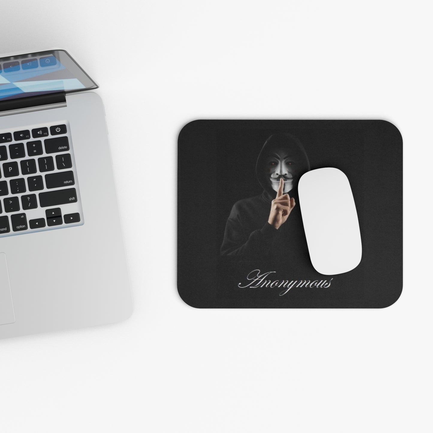 Black mouse pad with a white cat illustration next to a laptop on a white surface