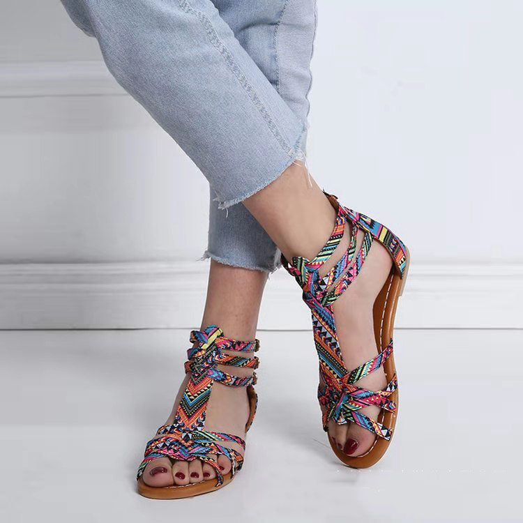 Colorful woven sandals worn with light blue jeans on a white background