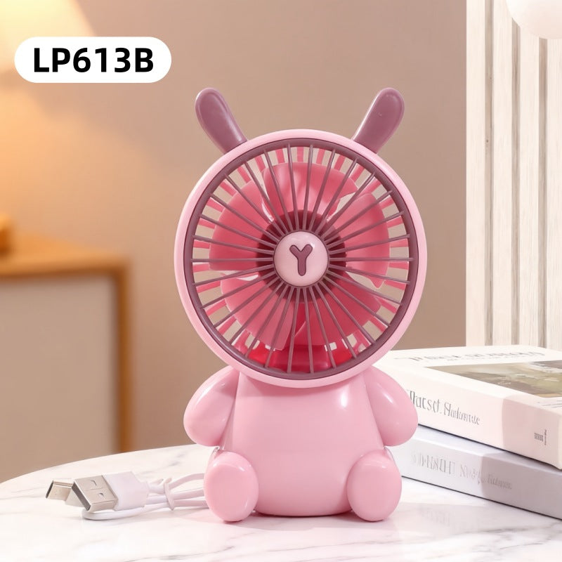 Pink rabbit-shaped fan on a surface with books in the background