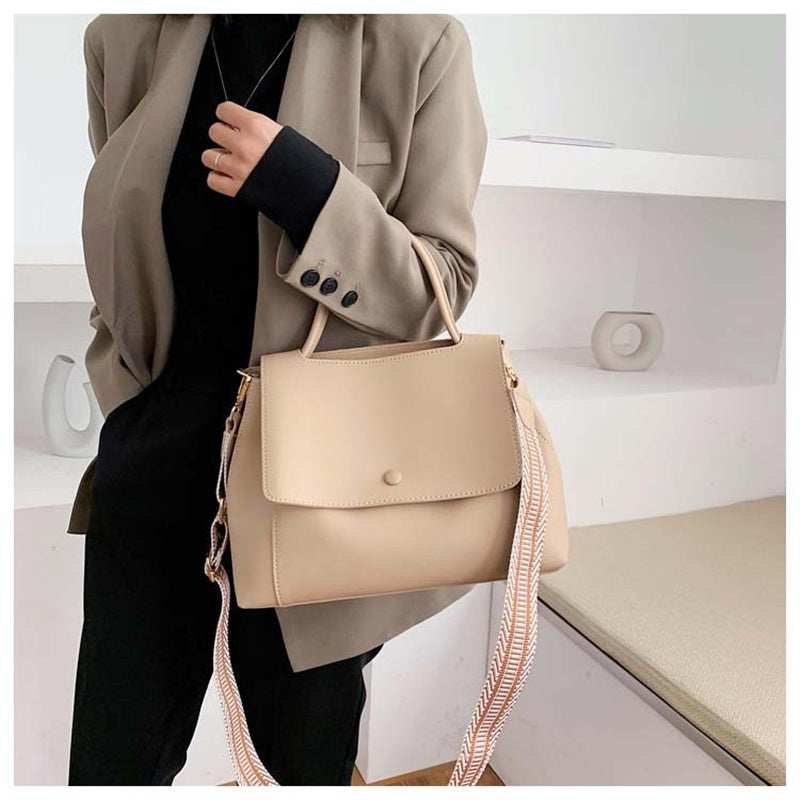Person holding a beige handbag with a white background