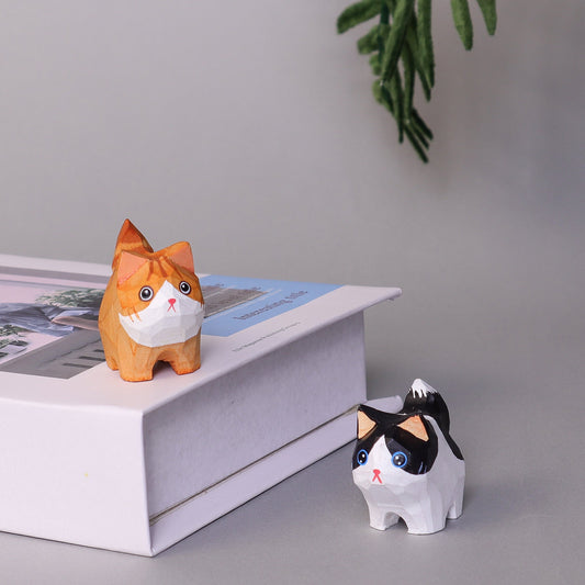 Two cat figurines on a surface with a gray background