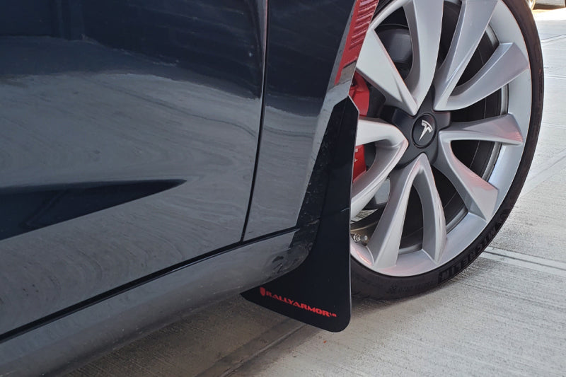 Car mud flap attached to a vehicle wheel on a concrete surface