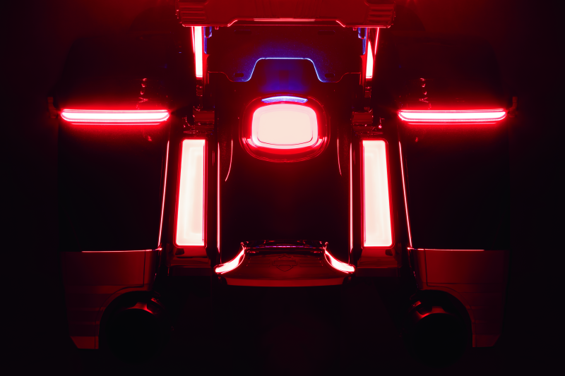 Close-up of a motorcycles tail lights with red and white illumination on a dark background