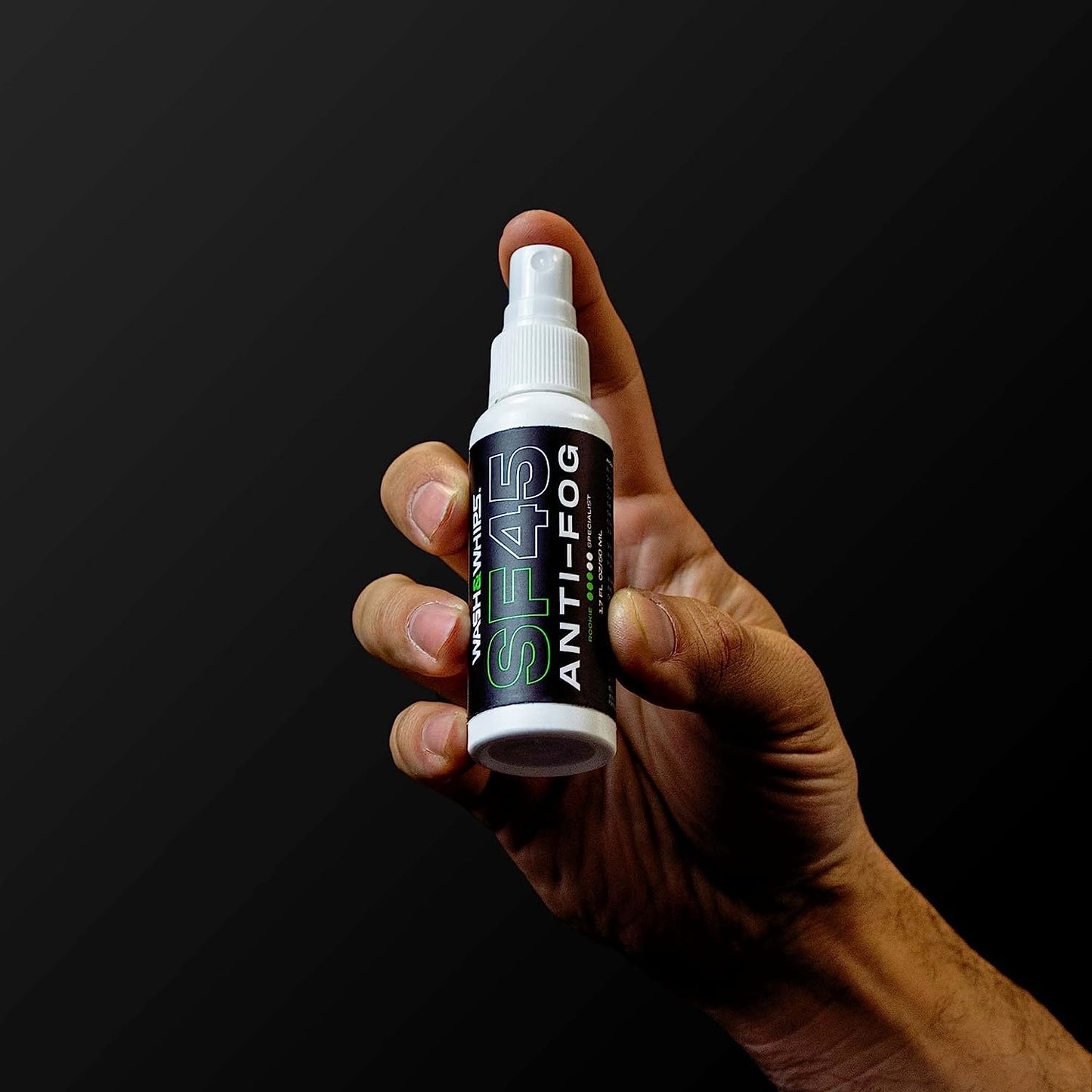 Hand holding a spray bottle labeled 'SP45 Anti-Fog' against a black background