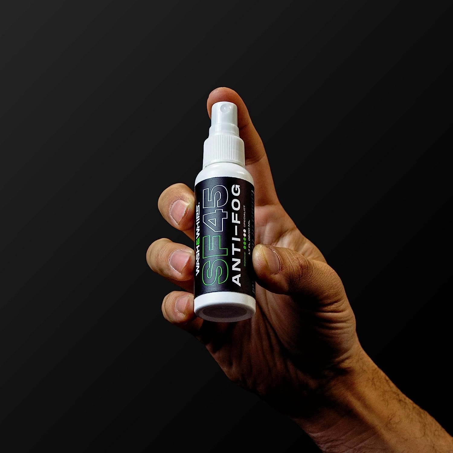 Hand holding a spray bottle labeled 'SP45 Anti-Fog' against a black background