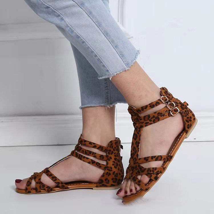 Leopard print sandals worn with light blue jeans on a white floor.