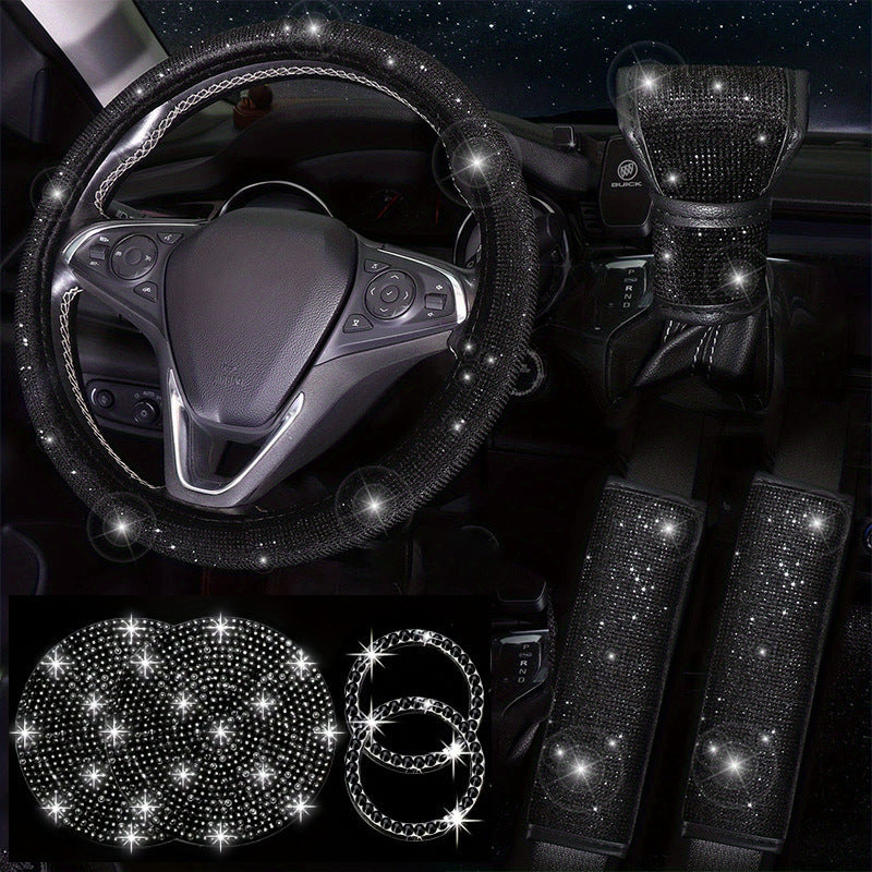Car interior set with bling steering wheel cover, seat covers, and headrests against a dark background.