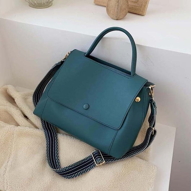 Teal handbag with a strap on a light surface