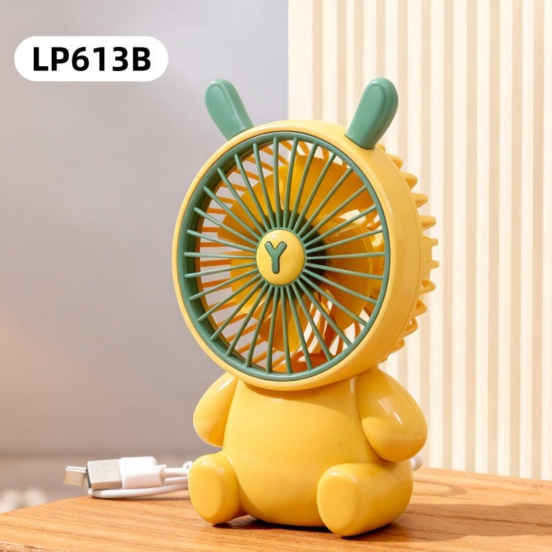 Yellow fan shaped like a bear with green accents on a wooden surface.