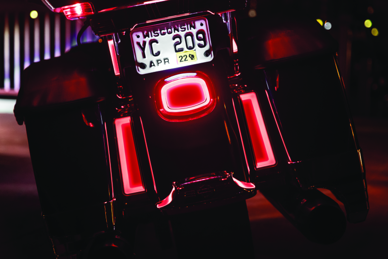 Close-up of a motorcycle with glowing red lights and a visible license plate at night.
