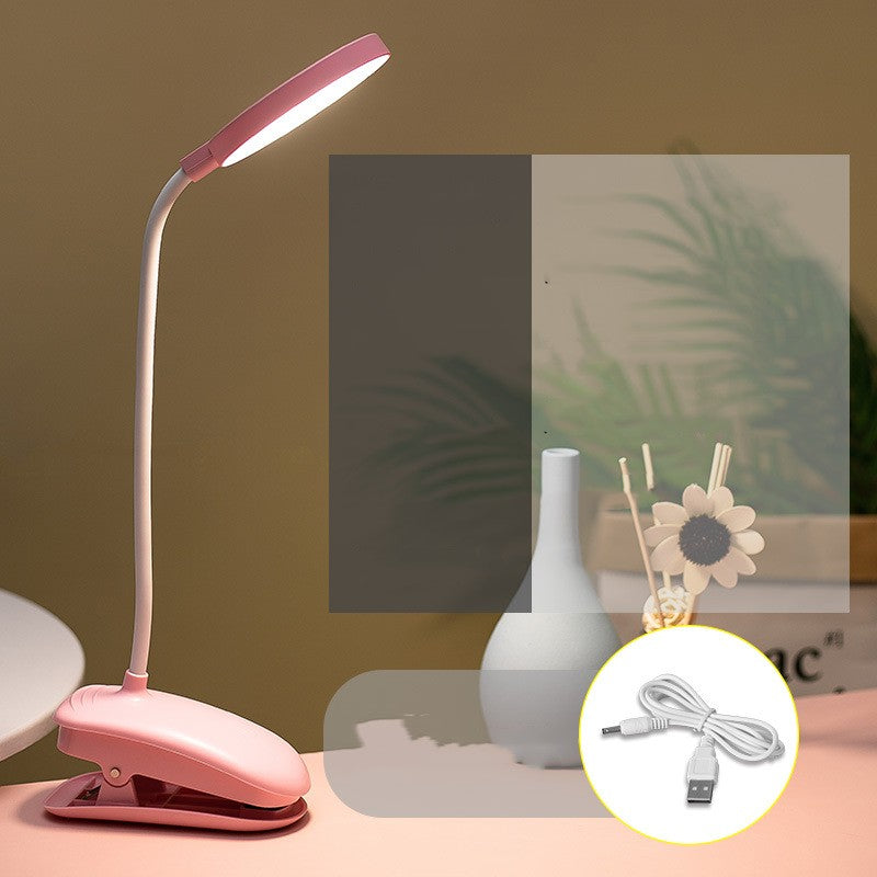 Pink desk lamp with USB cable on a table with a blurred background