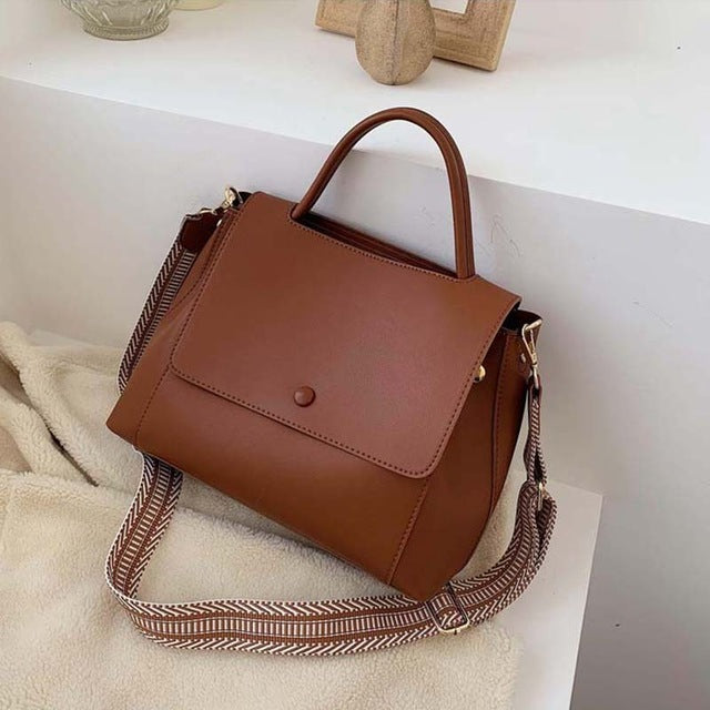 Brown handbag with a strap on a white surface